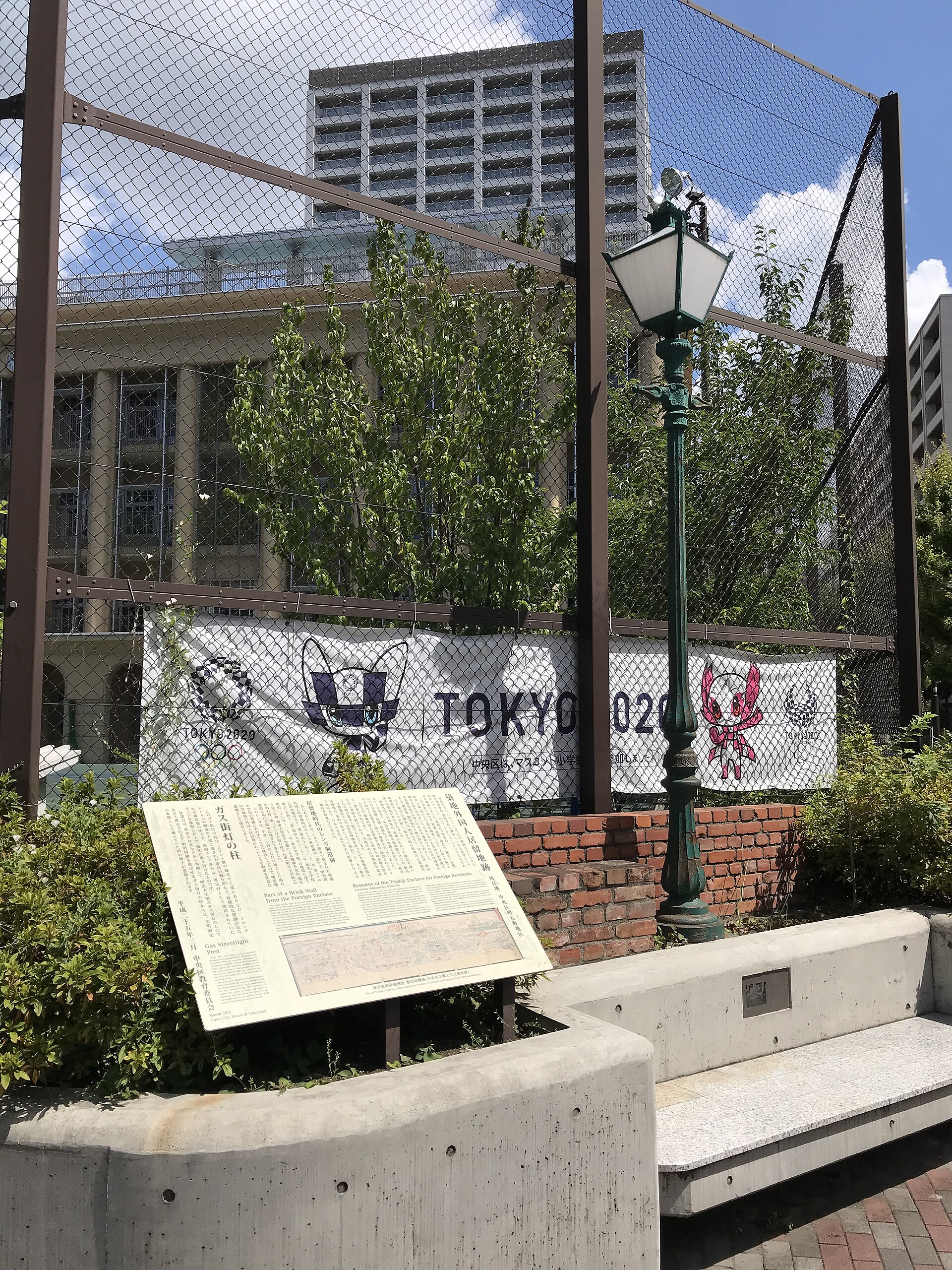 Memorial plaque for the Tsukiji foreign settlement beside a historic gas streetlight post in Akashicho