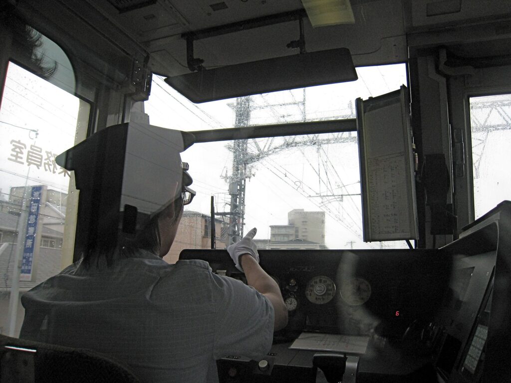 A railway worker pointing from a train cab in Japan