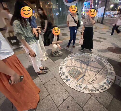 新宿三丁目の「新宿元標 ここが追分」を囲んで解説を聞く参加者