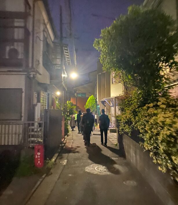 夜の田端・中里の細い住宅街を参加者が歩く様子