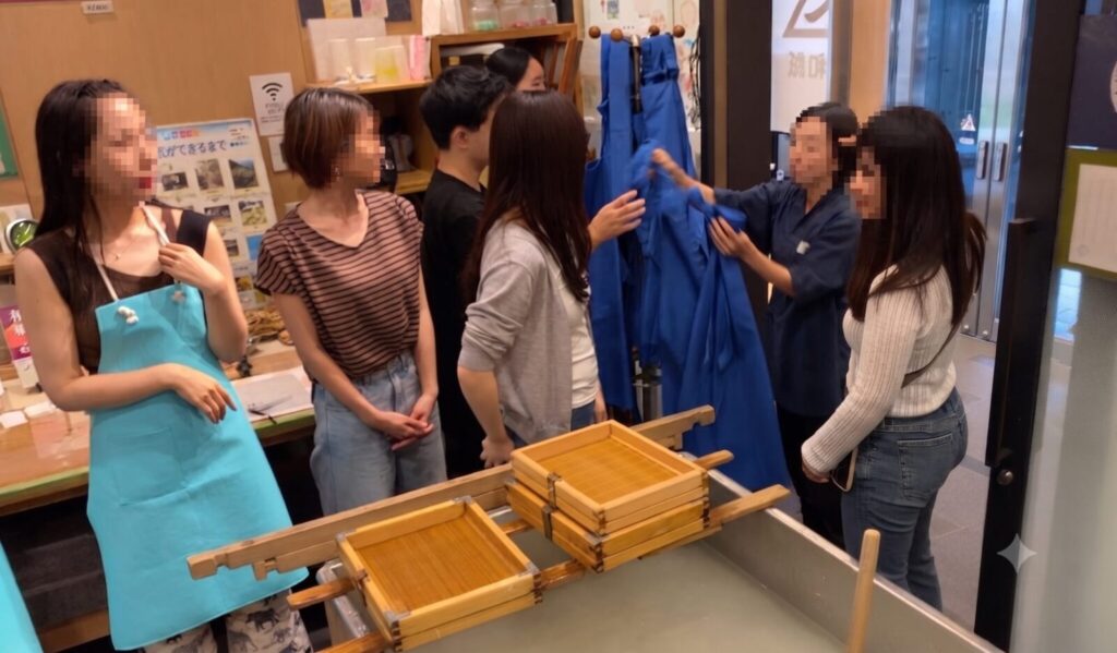 手漉き和紙体験の前にエプロンを着用する参加者