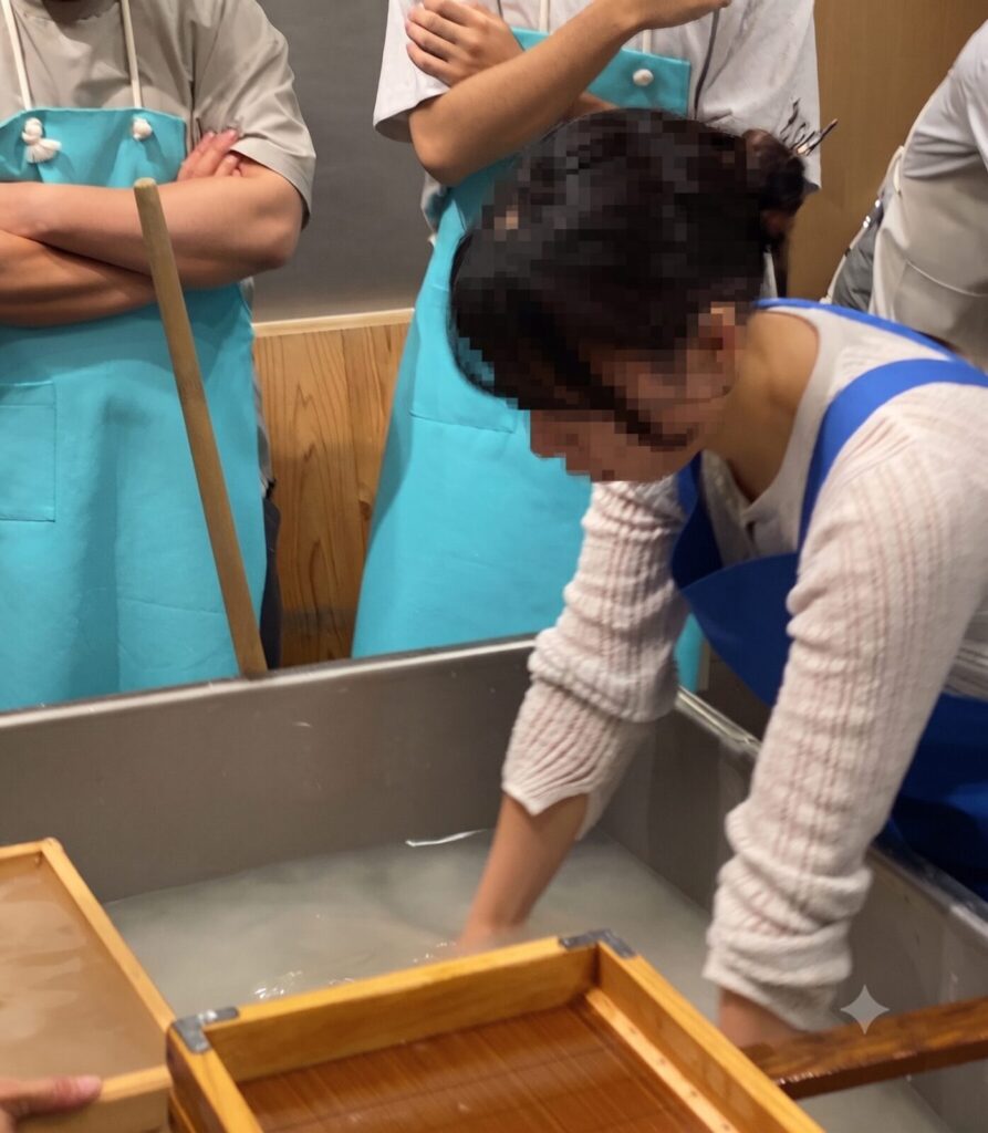 水槽に手を入れて一人ずつ手漉き和紙を体験する参加者
