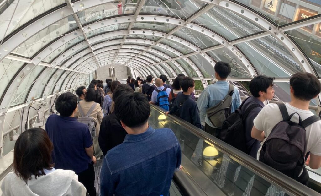 フジテレビ本社屋の長いエスカレーターを下る参加者