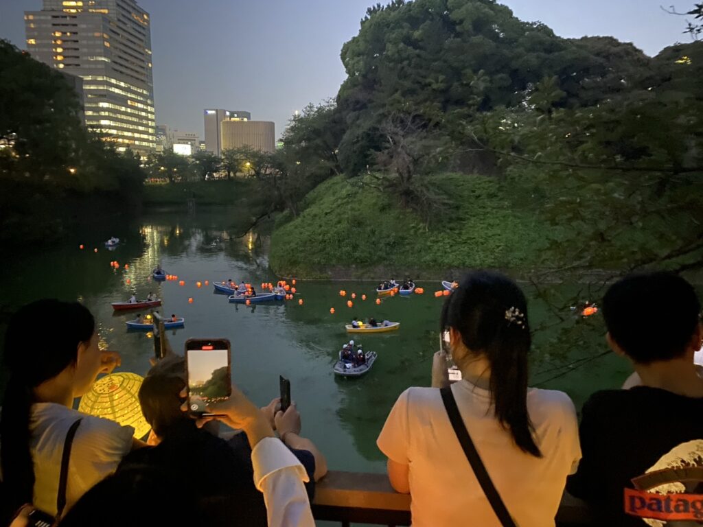 夕暮れの千鳥ヶ淵緑道から灯ろう流しを眺める参加者