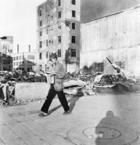 1945年9月、焼け跡を歩きながら新聞を読む男性