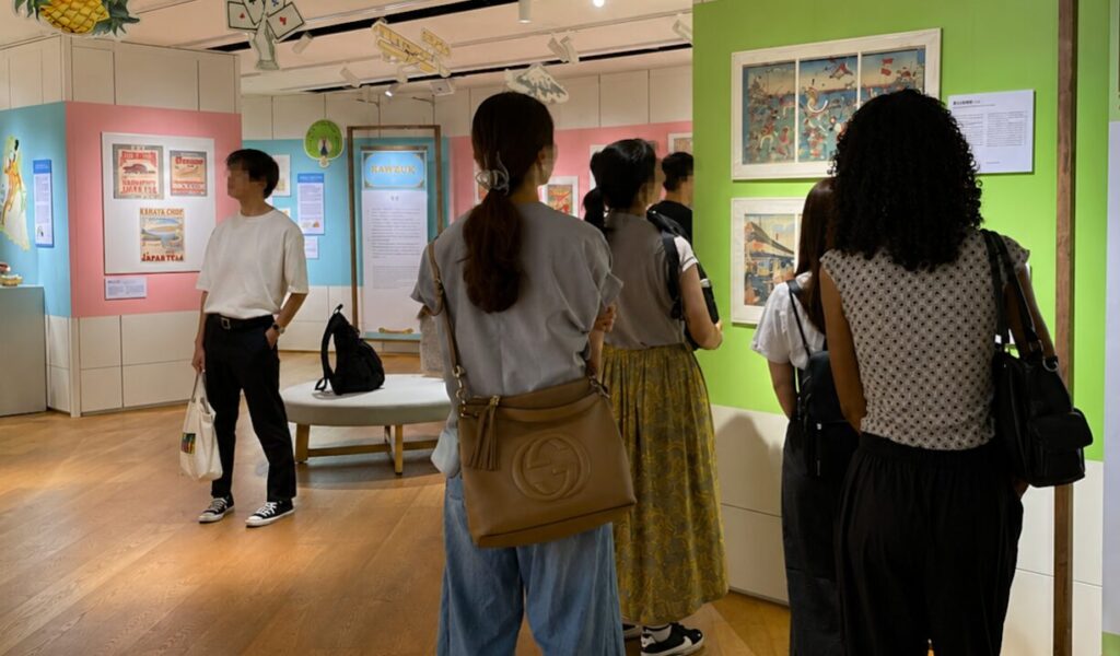 「世界を旅した小さなデザイン」展で輸出ラベルを見る参加者
