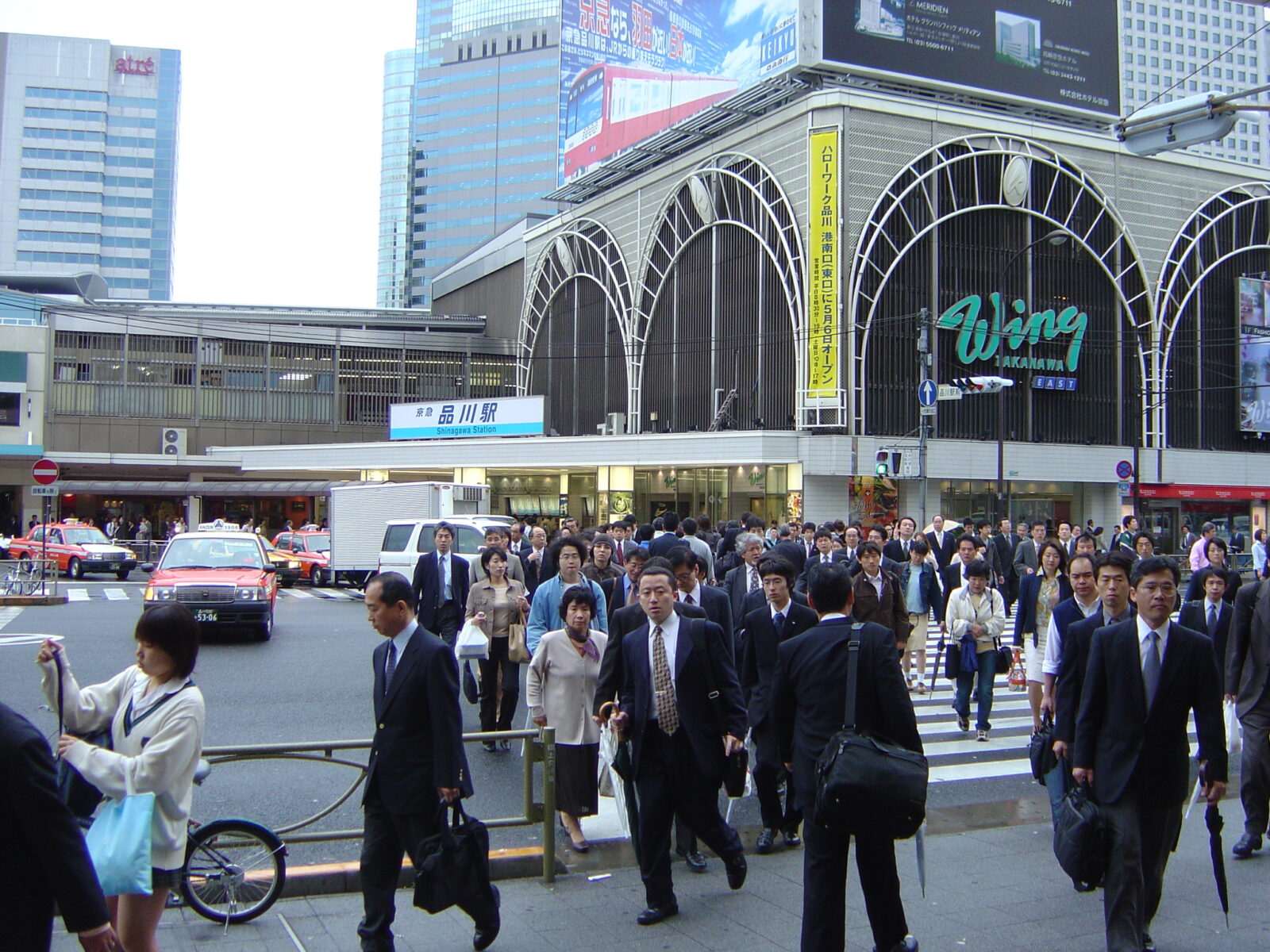 品川駅高輪口の駅舎と駅前を行き交う人々