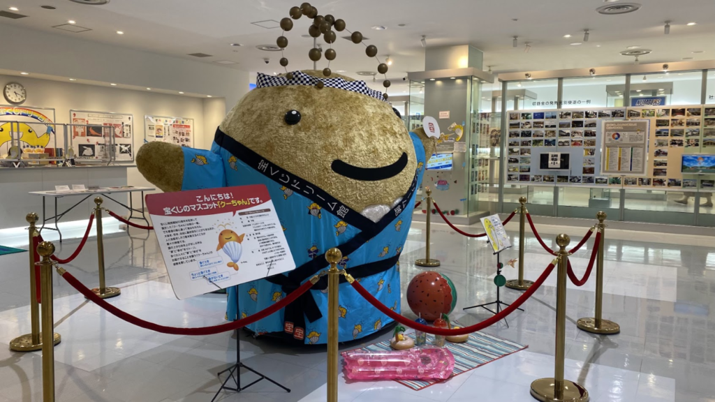 東京宝くじドリーム館で来館者を迎える宝くじマスコットのクーちゃん