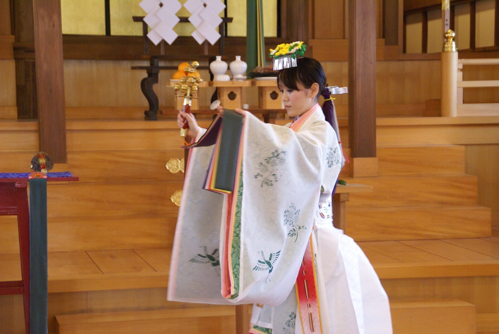 鈴を手に持ち装束を着けて舞う浦安の舞の舞姫