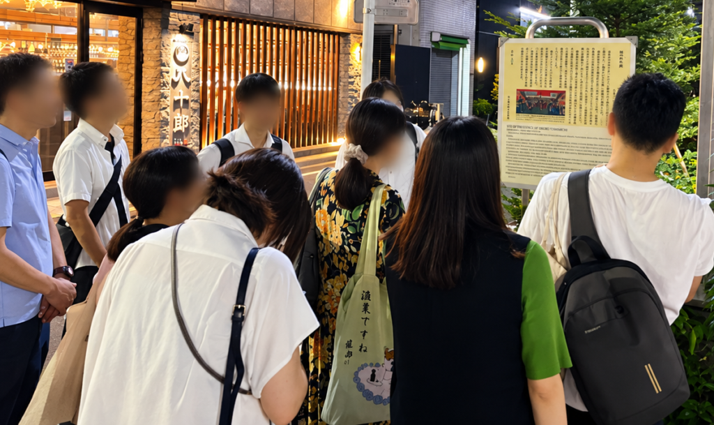 新富座跡の説明板を見学する参加者