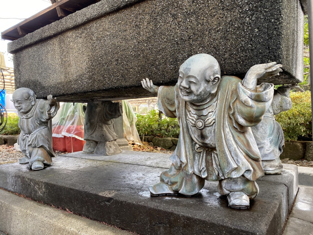 西新井大師境内の石を支える童子像