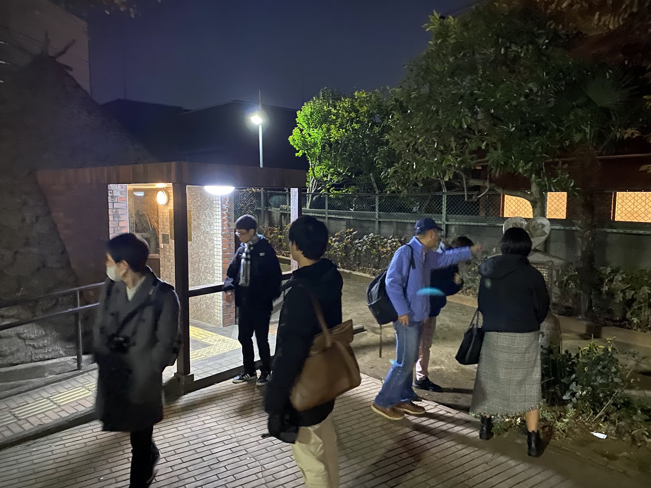 亀塚公園の竪穴式住居展示付近で解説を聞く参加者