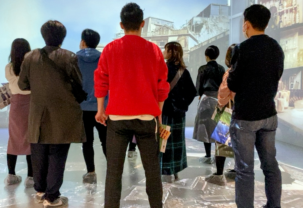 URまちとくらしのミュージアムの4面映像シアターを見学する参加者