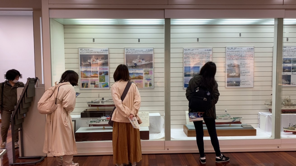 海洋情報資料館で測量船模型の展示を見る参加者