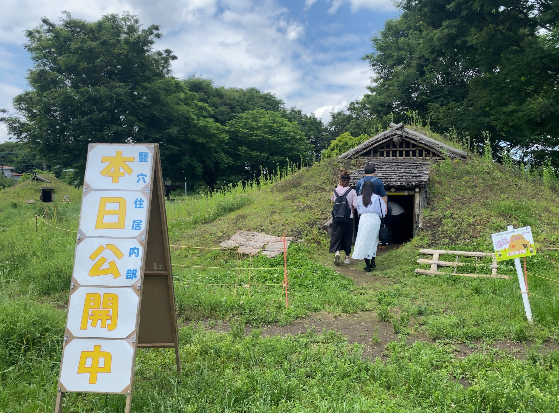 下野谷遺跡公園の復元竪穴住居を見学する参加者