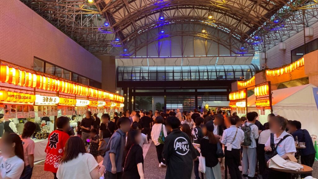 夕暮れのアーク・カラヤン広場を彩る秋祭りの提灯と屋台