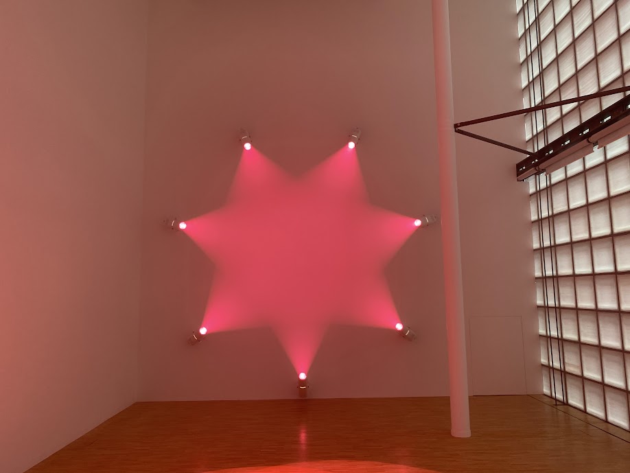 アン・ヴェロニカ・ヤンセン《Rose》のピンク色の光が星形に広がる展示風景