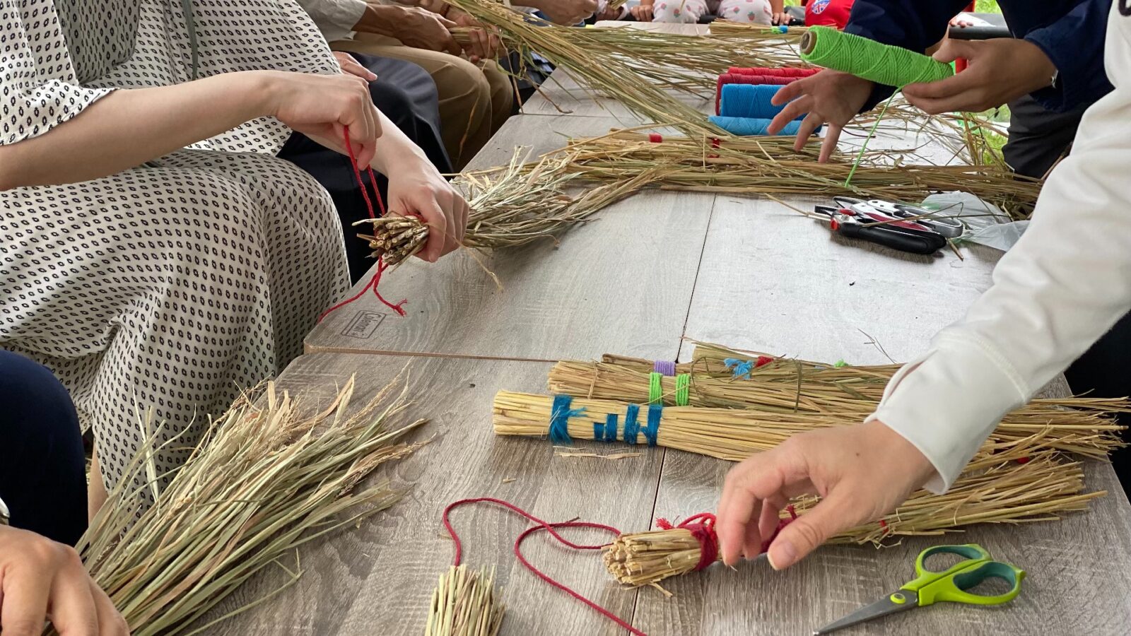 おおはし里の杜一般公開で稲わらを束ねてミニほうきを作る体験の様子