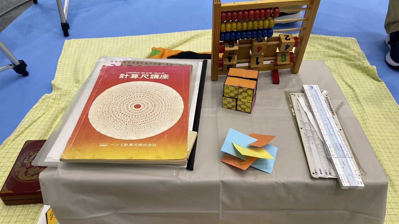 東京理科大学ブースに並ぶ計算尺やそろばんなどの計算道具