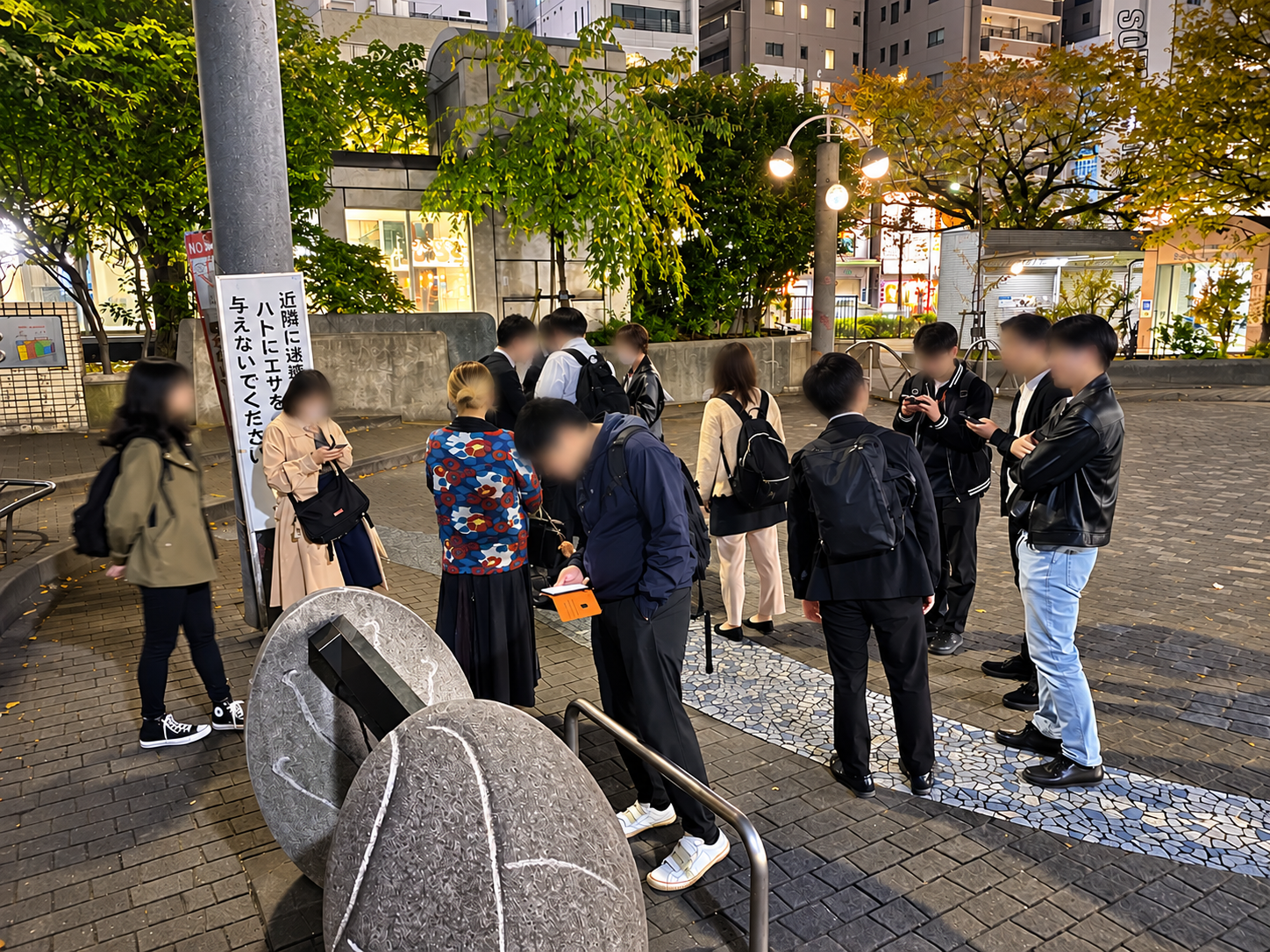 夜の駒込駅付近に集合した街歩きの参加者