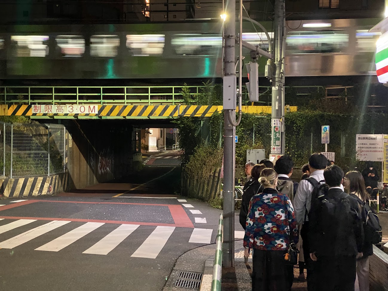 鉄道高架下の夜道を歩く歴史散歩の参加者