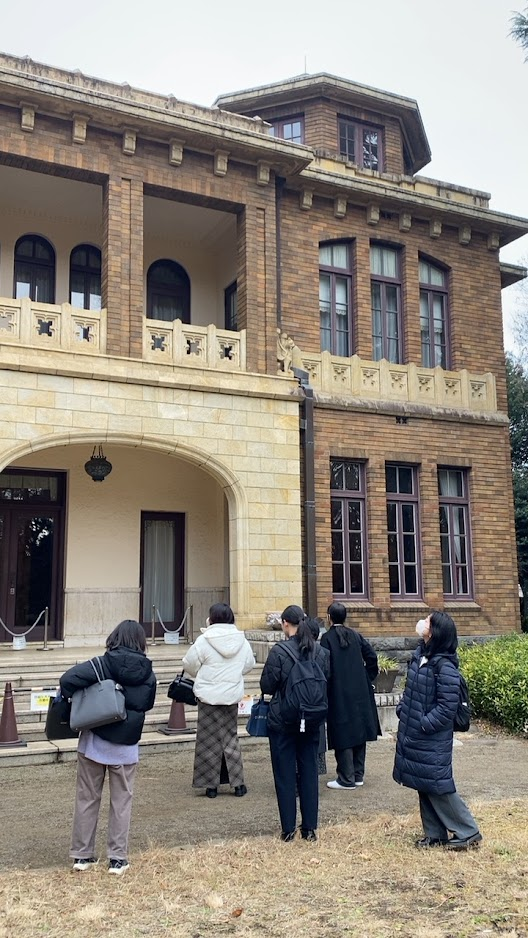 旧前田家本邸洋館の外壁とバルコニーを見上げる見学参加者