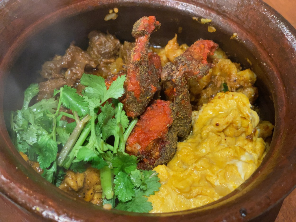 土鍋に盛られた南インド風のスパイス料理と卵 パクチーを添えた一品