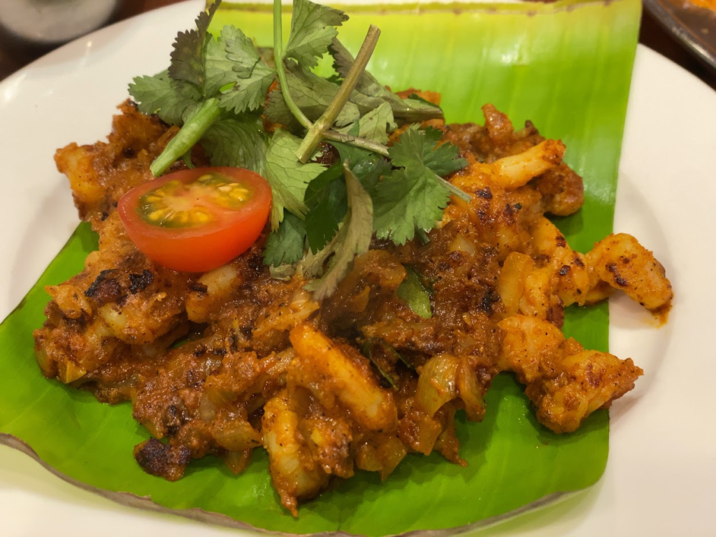 バナナの葉に盛られた南インド料理のスパイシーな炒め物 トマトと香草添え