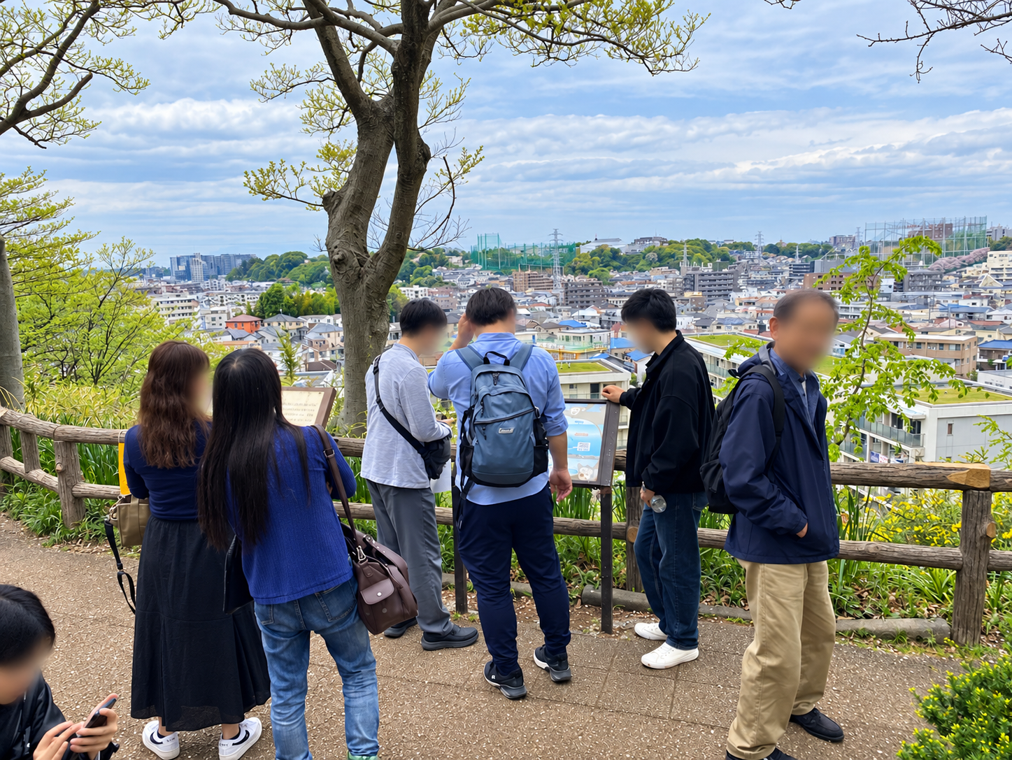 夢見ヶ崎動物公園の高台から市街地を眺める散歩参加者と春の景色