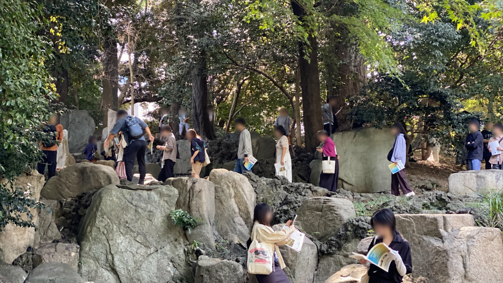 懐徳館庭園の三段の滝石組付近を歩く見学者と積み重なる大きな庭石