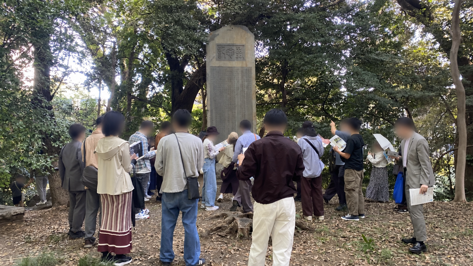 懐徳館庭園の行幸記念碑の前で説明を聞く見学者たち